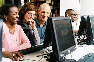 adults looking at computer screen in computer lab