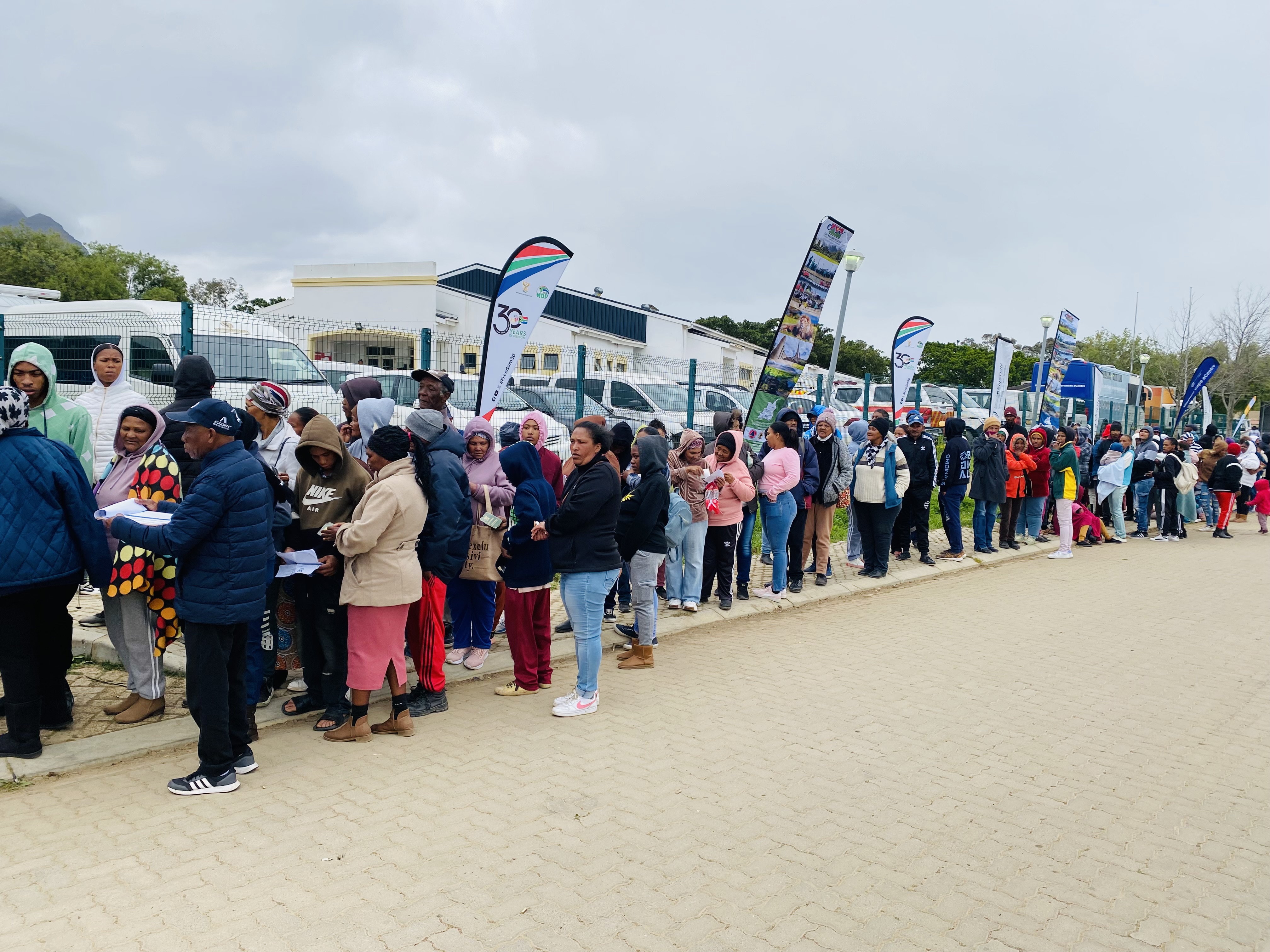 Braving the cold, Saron community members queue for essential services from various government departments, showcasing the critical importance of outreach efforts in meeting their needs