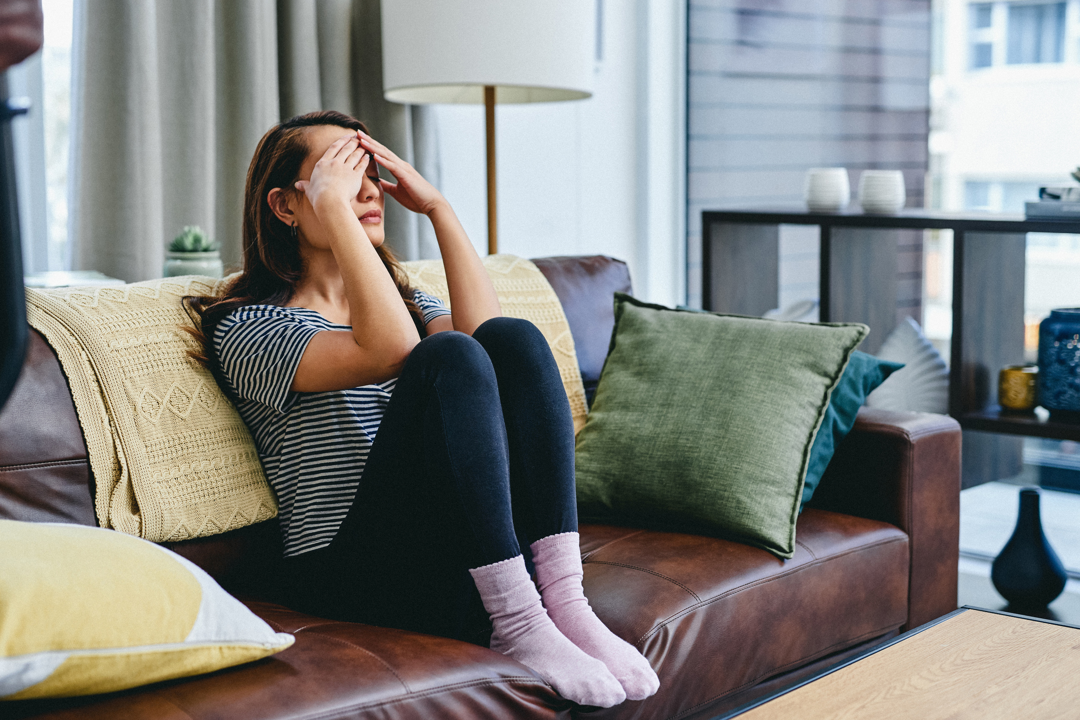 A young woman looking stressed while sitting at home