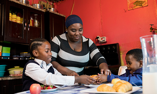 mom and two children preparing breakfast.