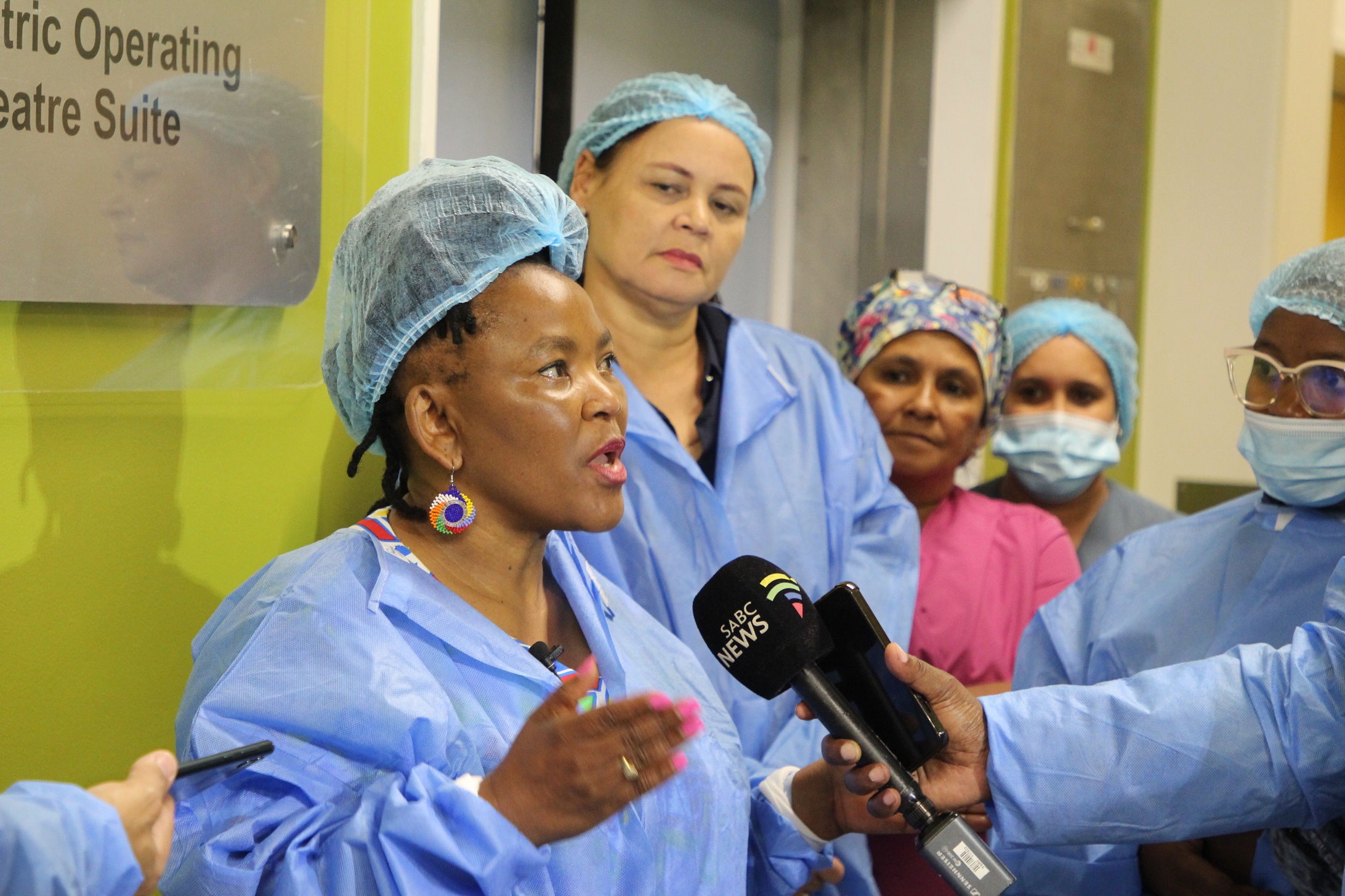 Minister Mbombo briefing the media outside the theatre rooms in which a live robotic surgery was taking place.