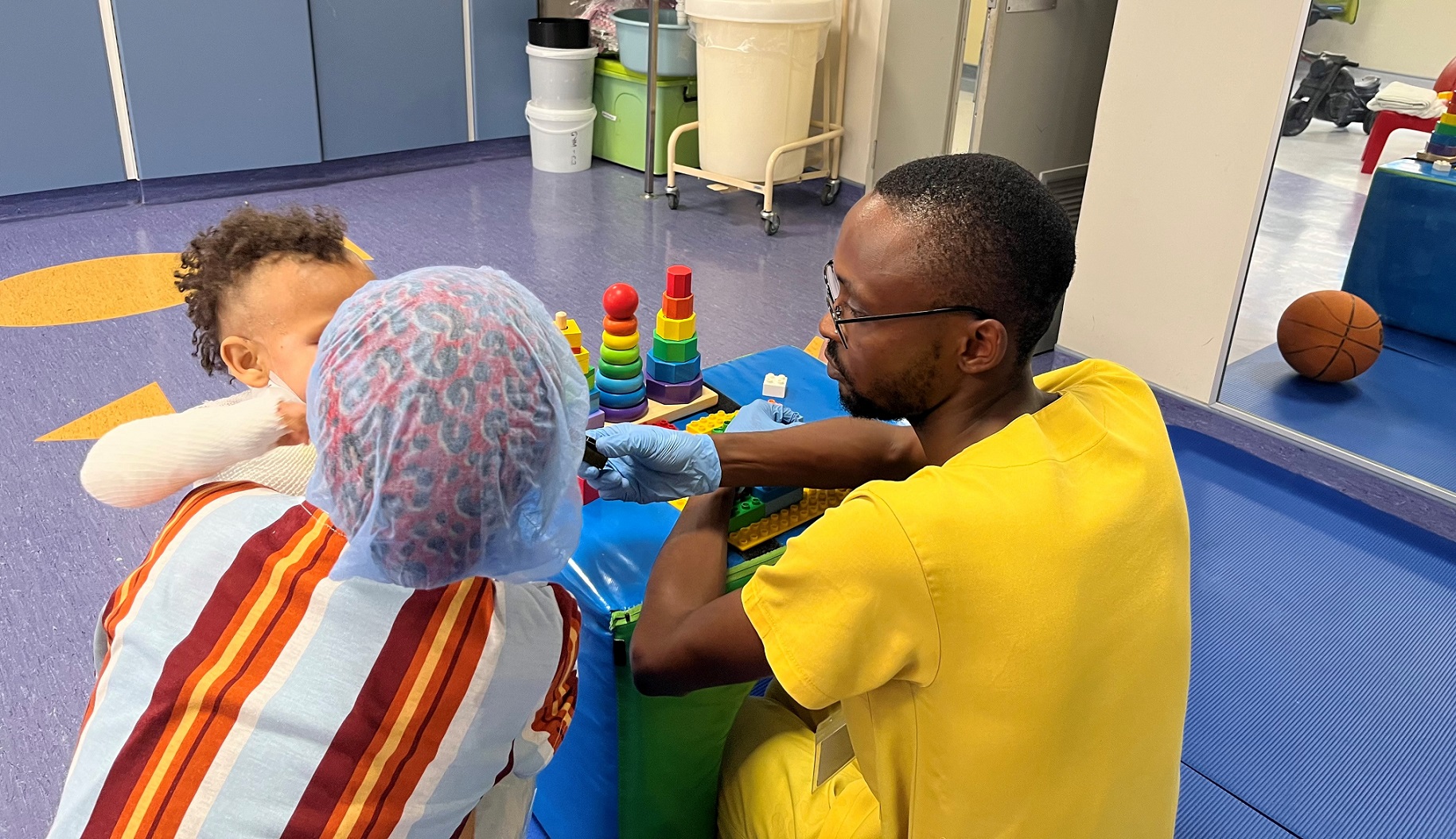 Occupational therapist Irvin Mwadira provides support to a young patient and his mother at the Red Cross War Memorial Children’s Hospital.