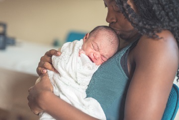 Young mother kissing her newborn baby 